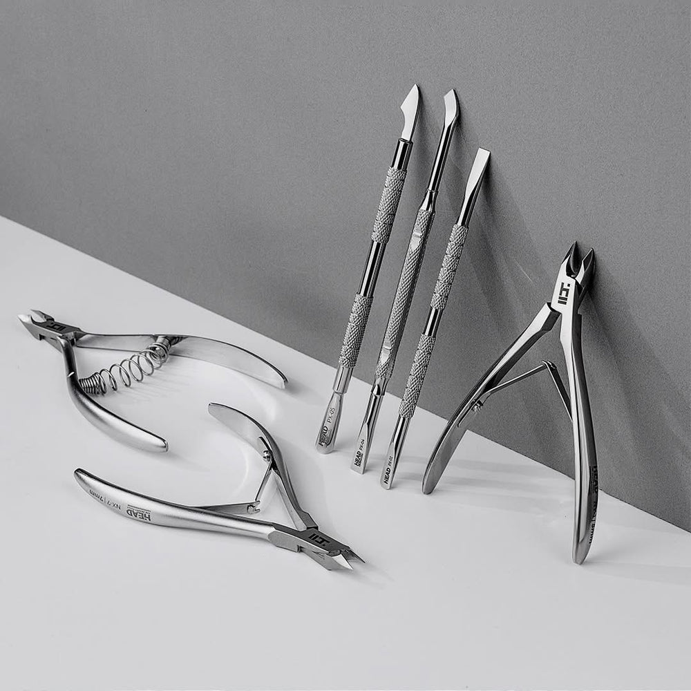 Set of silver nail tools on a white surface with a gray background